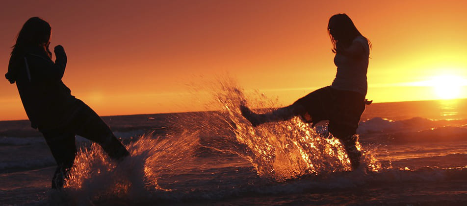 Ausgelassene Wasserschlacht im Sonnenuntergang am Meer dank Schuldenhilfe von Schuldnerberater Schuldner-Hotline Bremen Borgfeld